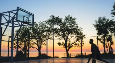 Boy playing basketball at sunset
